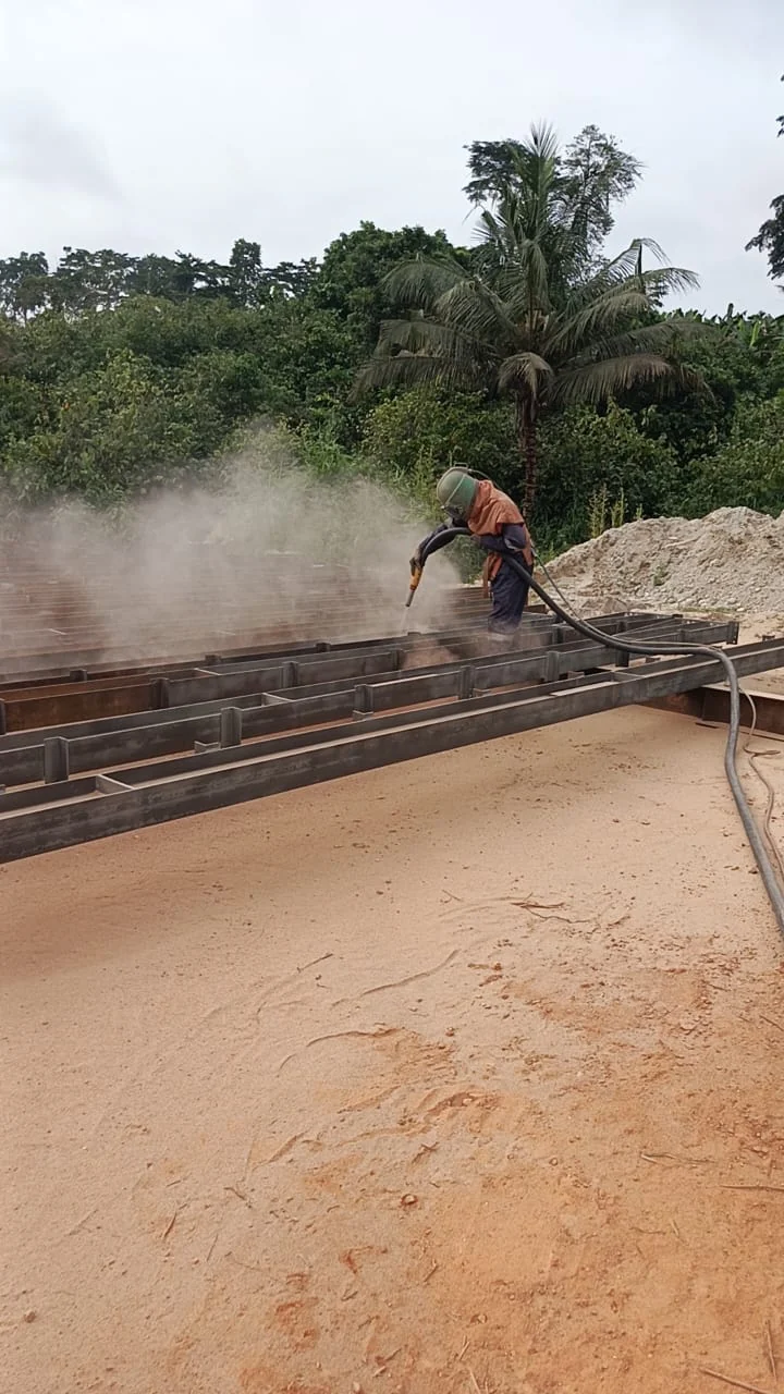 Worker preparing structural steel with surface cleaning equipment
